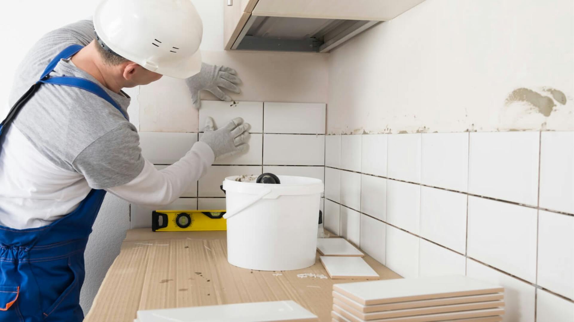 Person fliest Küchenzeile mit weißen Fliesen.