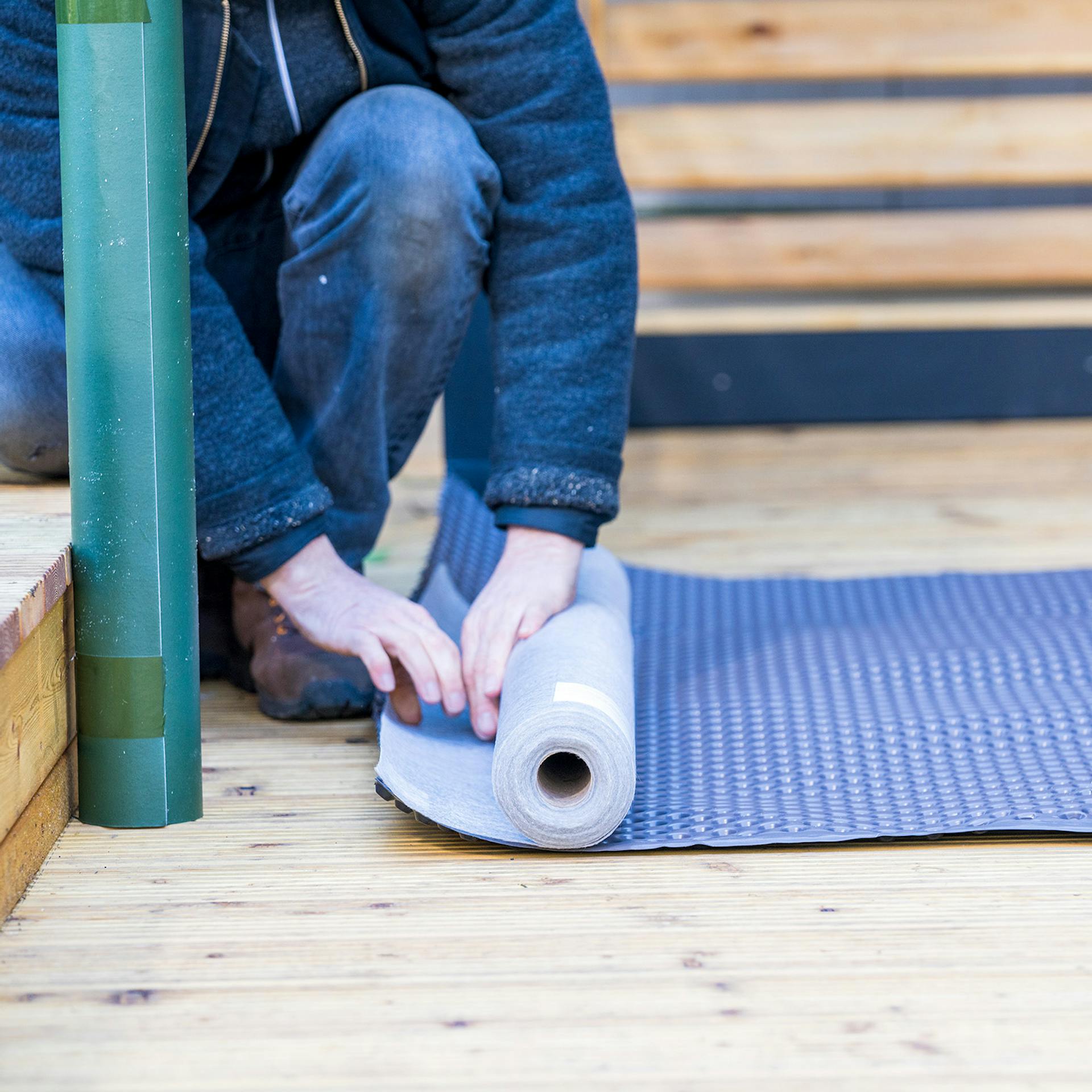 Mann rollt Wurzelfolie aus und nimmt die Maße.