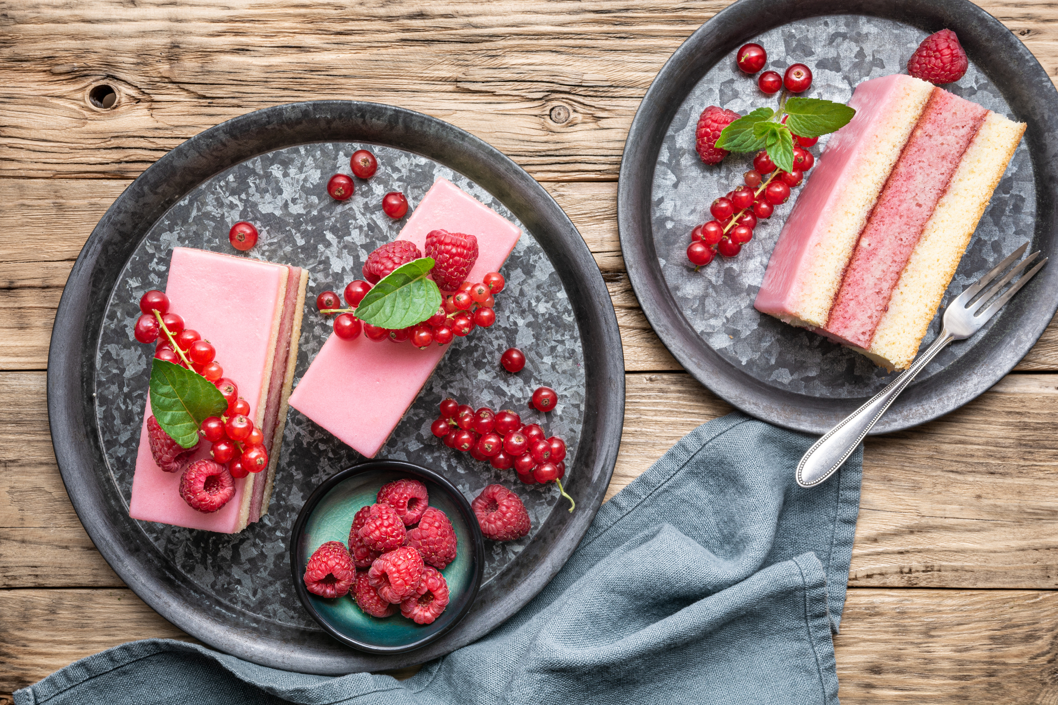 Johannisbeerkuchen liegt auf zwei Tellern garniert mit Himbeeren.