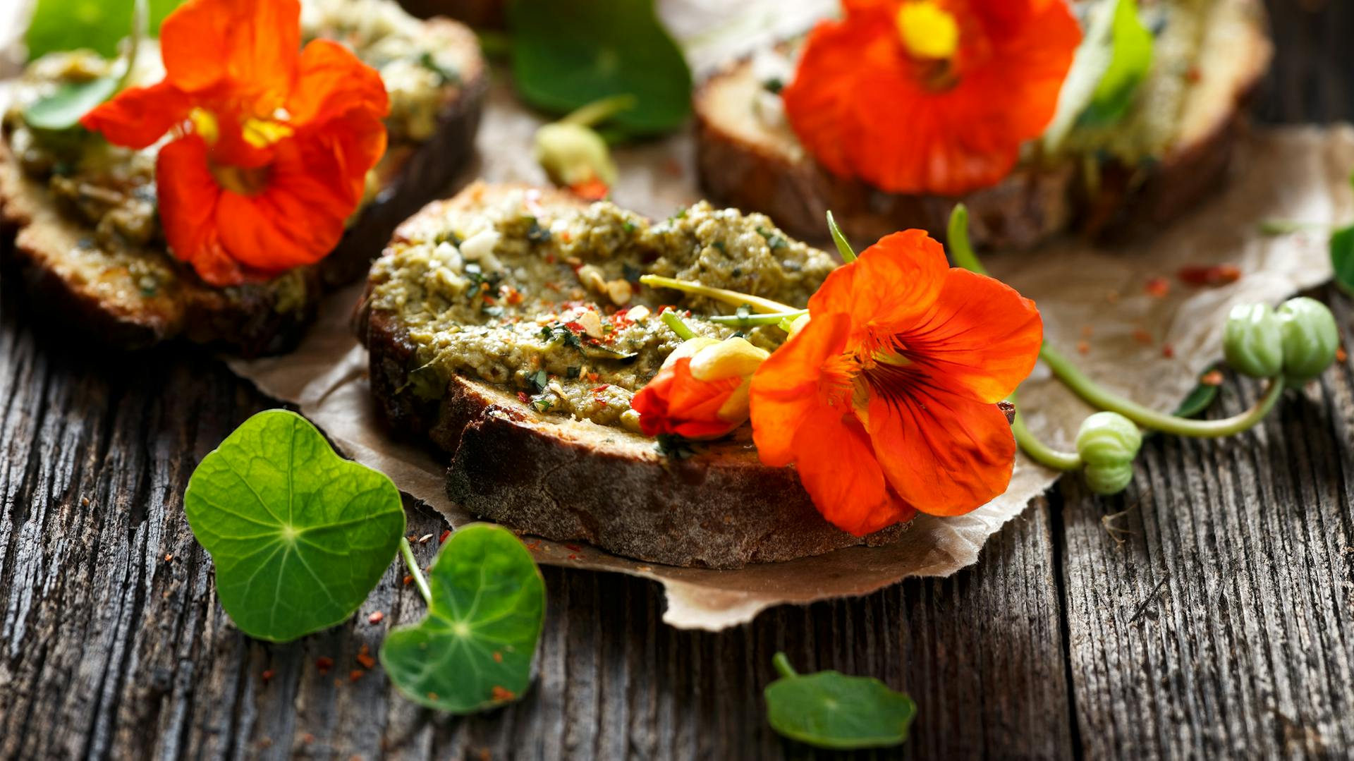 Blätter und orangefarbene Blüten der Großen Kapuzinerkresse auf Brot.