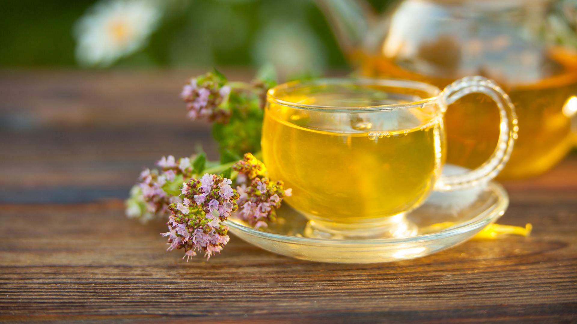 Majoran-Tee in einer Glastasse mit Majoranblüten verziert.