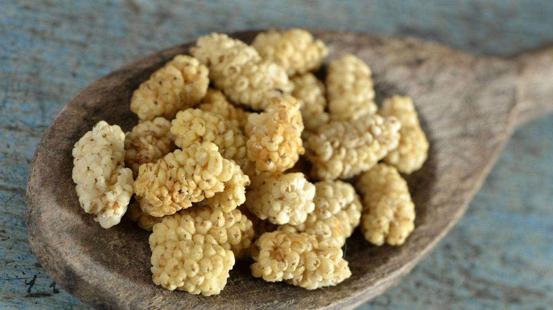 Getrocknete weiße Maulbeeren liegen auf einem Holzlöffel.
