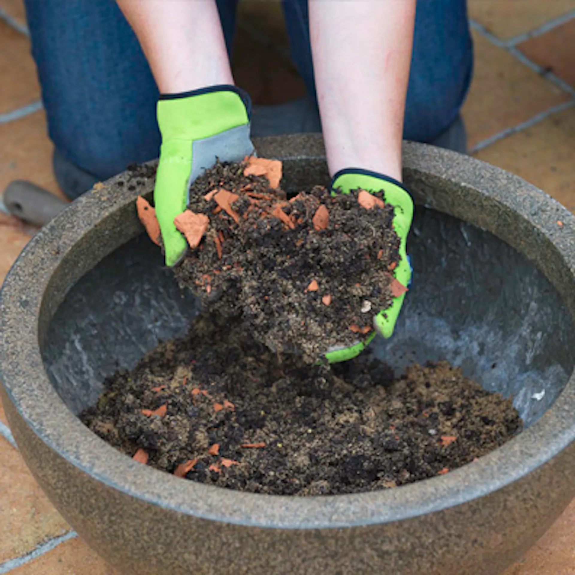 i frammenti di argilla vengono mescolati con il terriccio come strato di drenaggio in una fioriera.