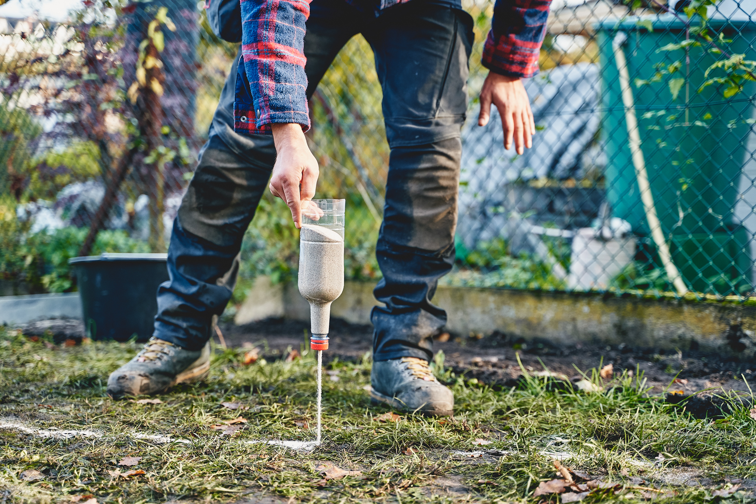 Egy férfi az ágyás szélét homokkal jelöli ki.
