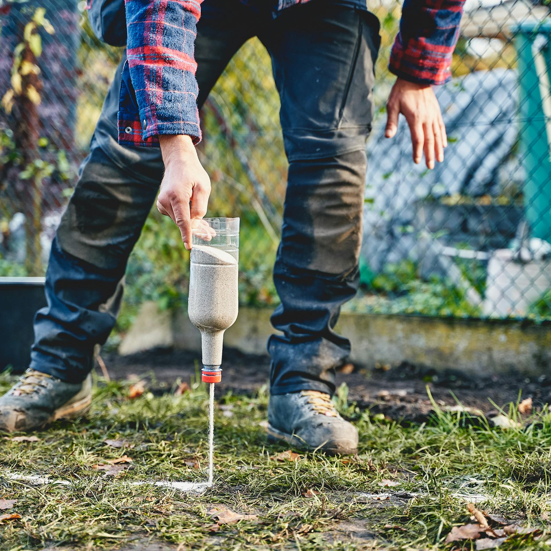 Egy férfi az ágyás szélét homokkal jelöli ki.