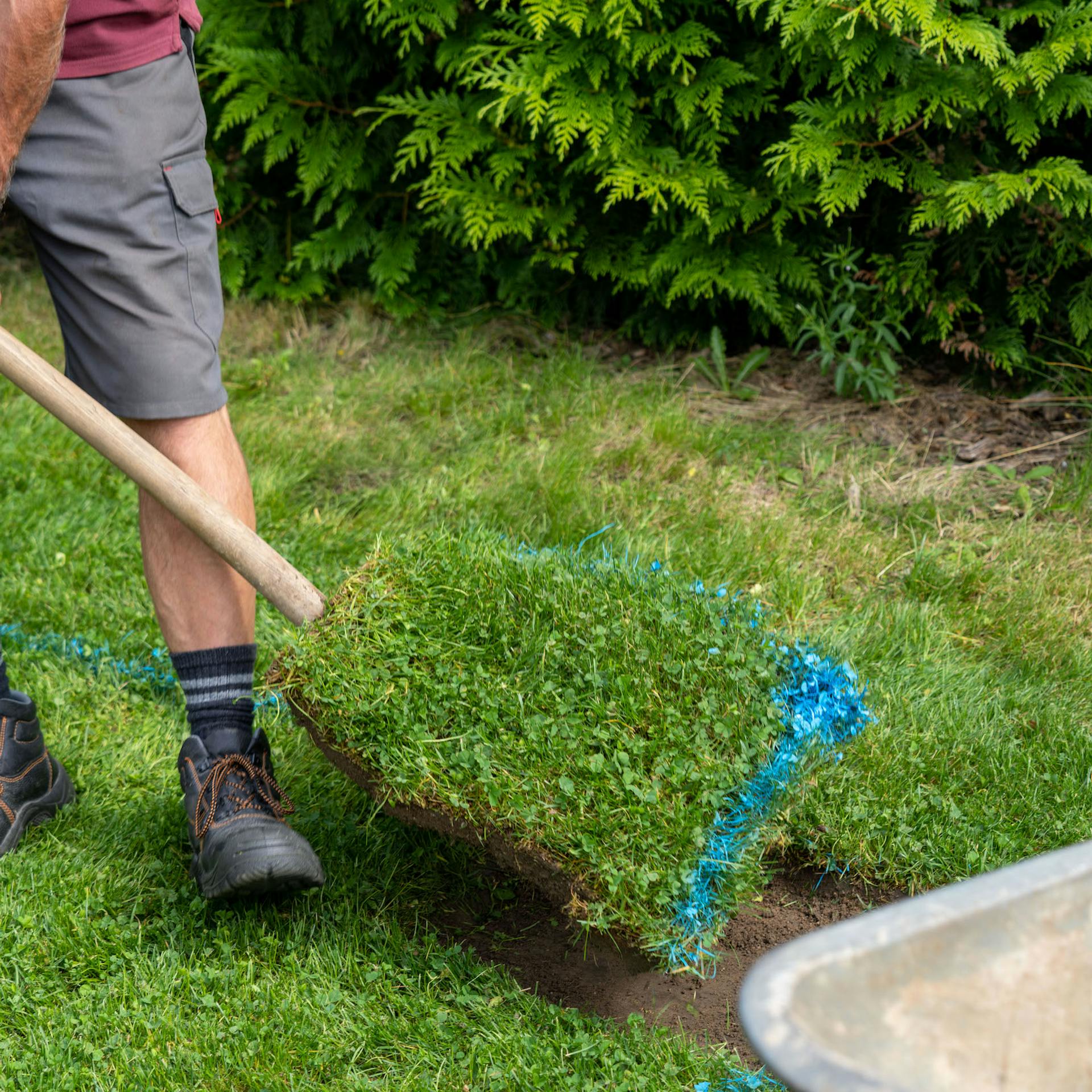 Muž odstraňuje rýčem travní porost