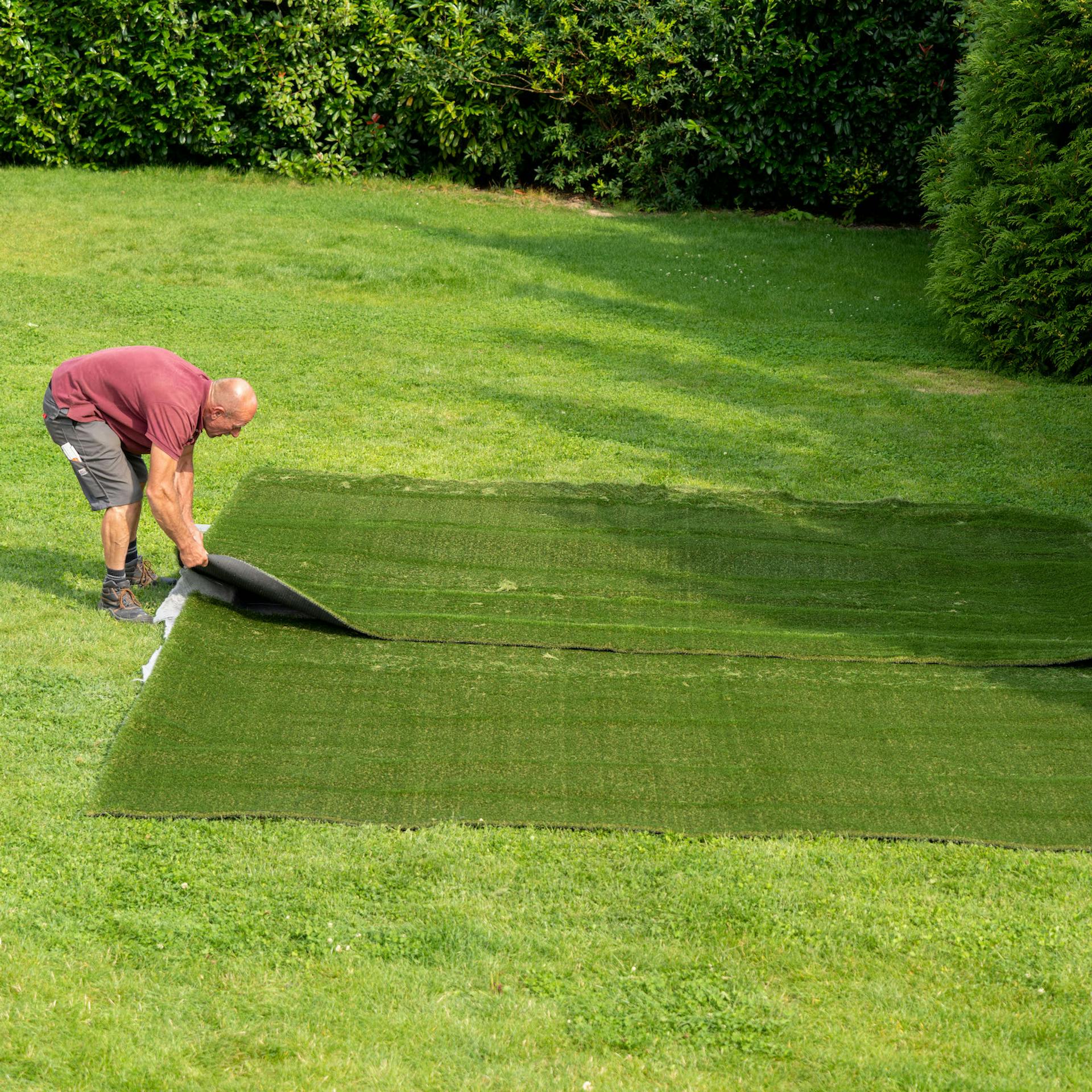 Dvě osoby pokládají umělý trávník