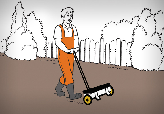 A kerti dolgozó füvet vet egy szórókocsi segítségével