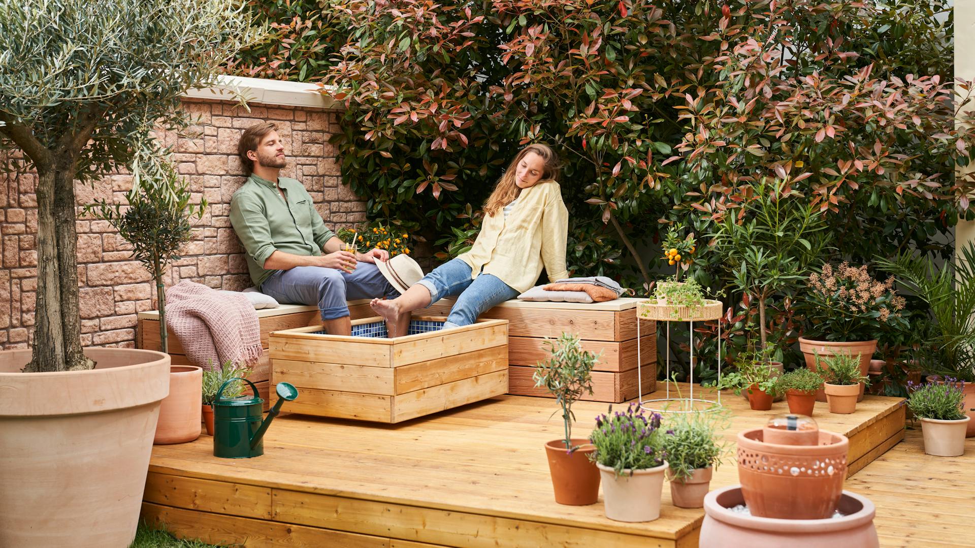 Paar sitzt auf Bänken mit den Füßen in einem Fußbad