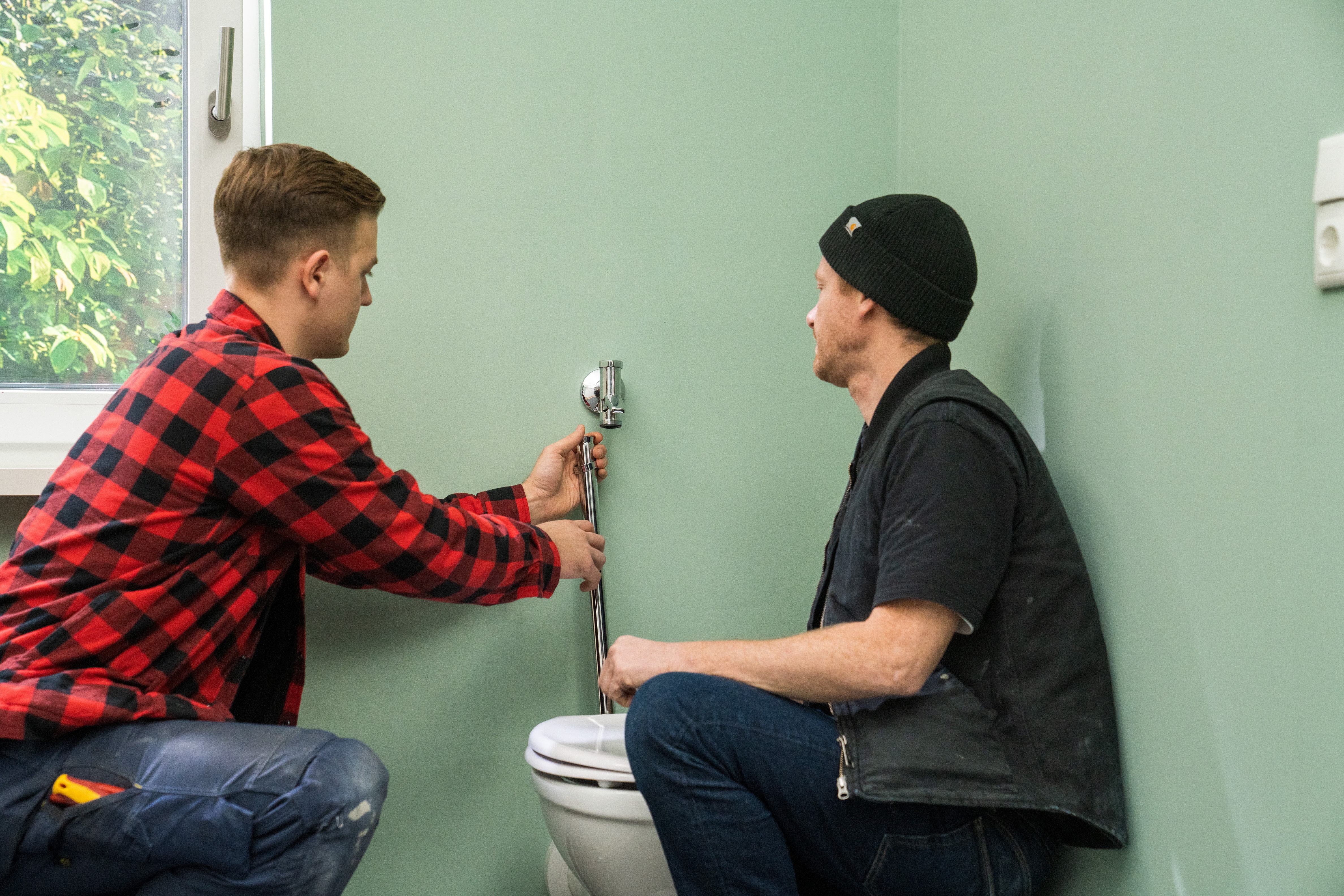 Handwerker entfernt das alte Rohr zwischen Druckspüler und WC.