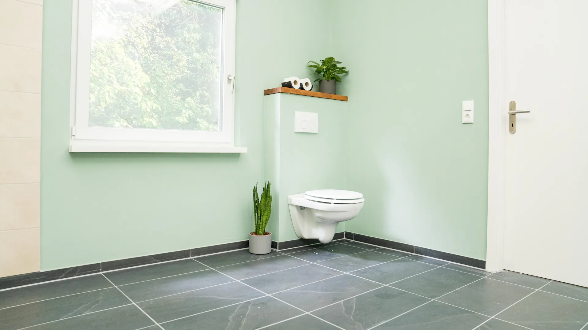 Wand-WC vor türkiser Wand