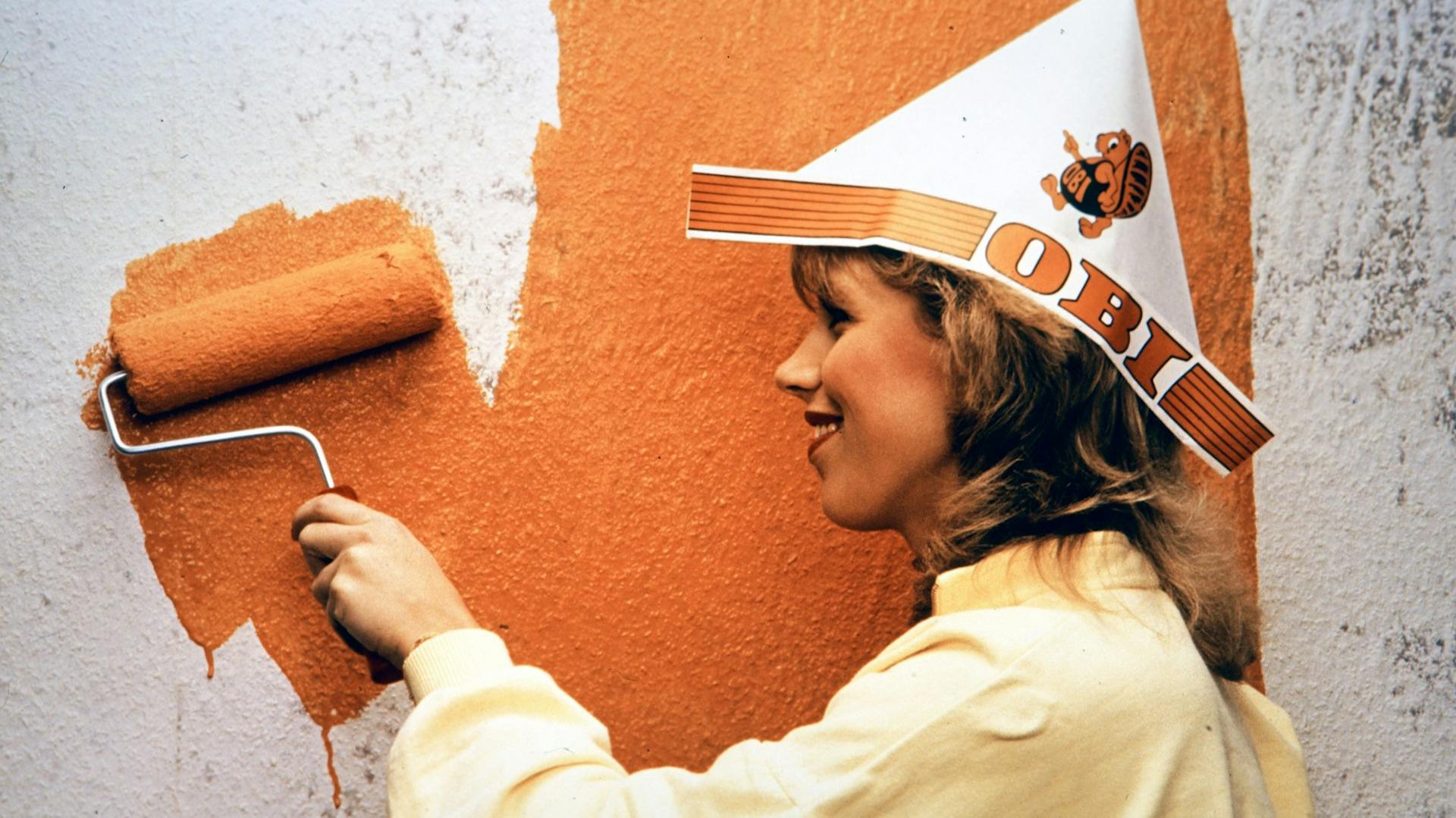 Frau malt eine Wand in Orange