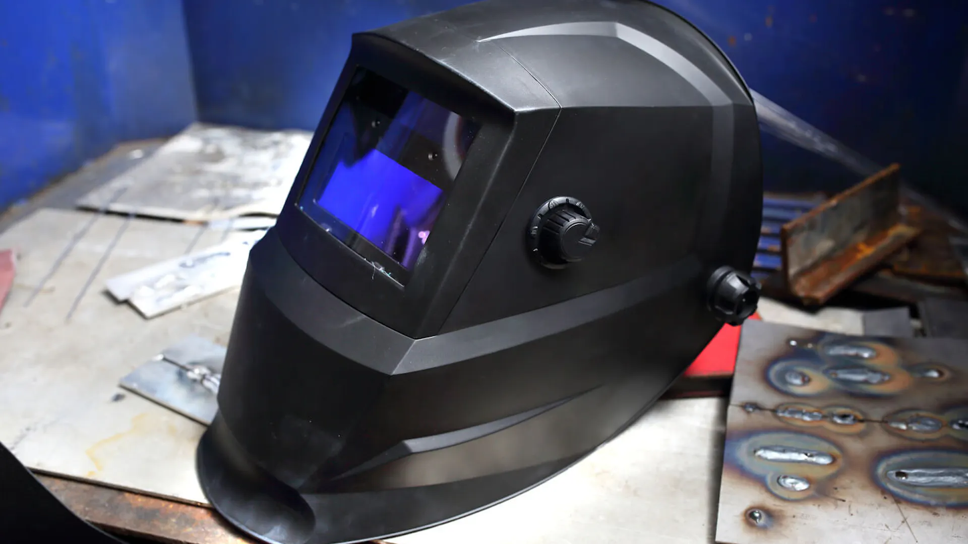 Przyłbica spawalnicza samościemniająca leży na stole w warsztacie