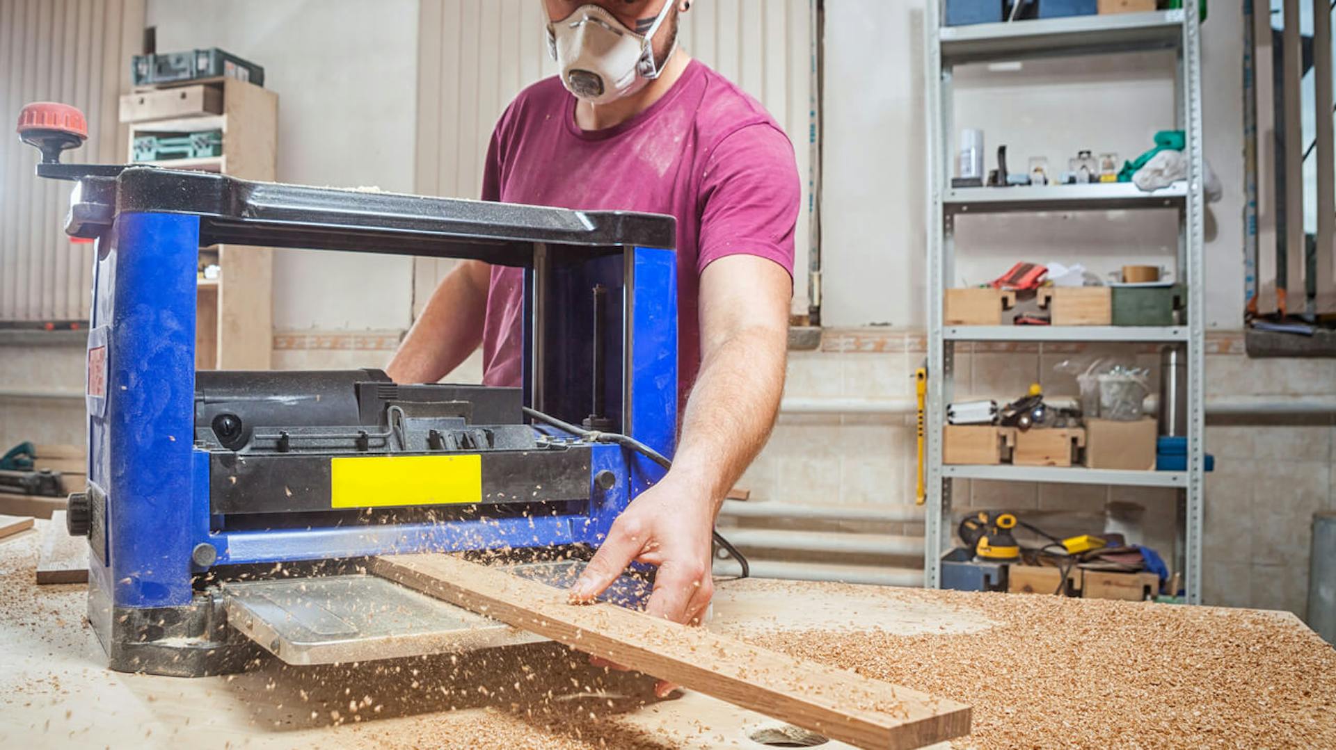 Mężczyzna pracuje w warsztacie stolarskim używając grubościówki