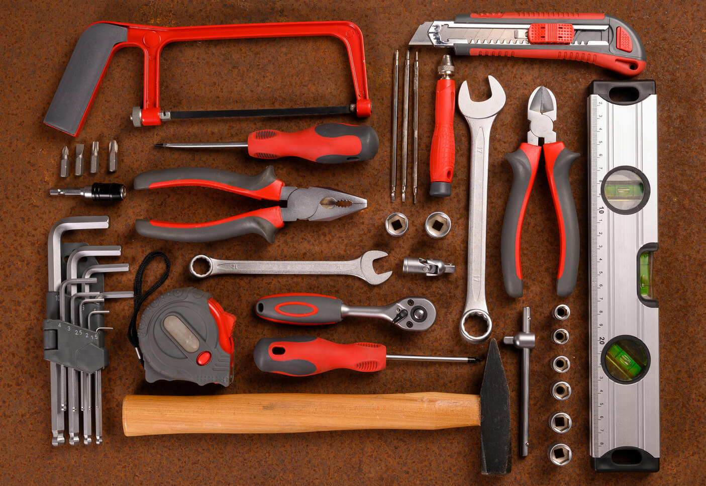 Zestaw narzędzi ręcznych leży na brązowym blacie.