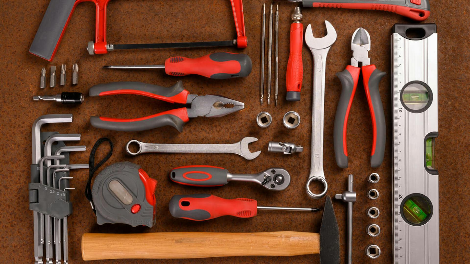 Zestaw narzędzi ręcznych leży na brązowym blacie.