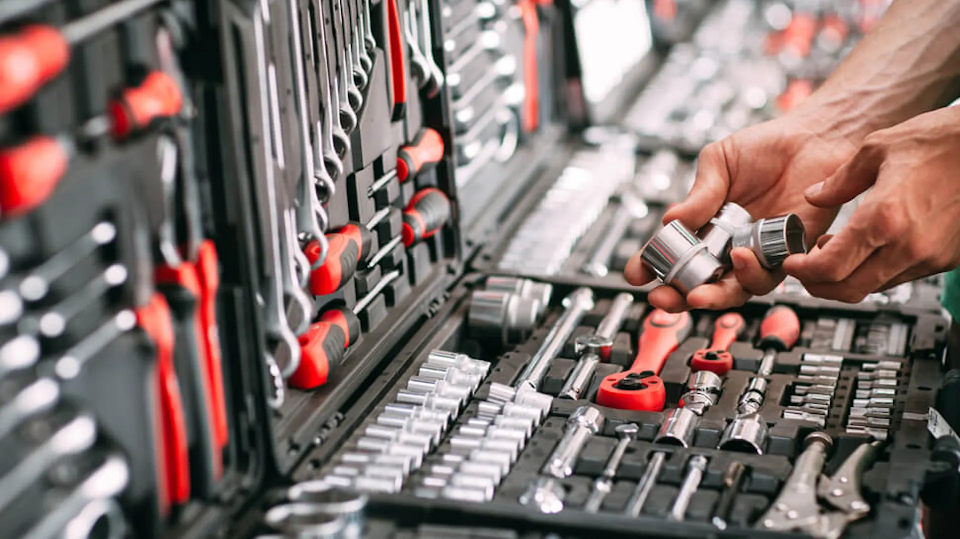 Mężczyzna wybiera z walizki z narzędziami odpowiednią metalową nakrętkę.