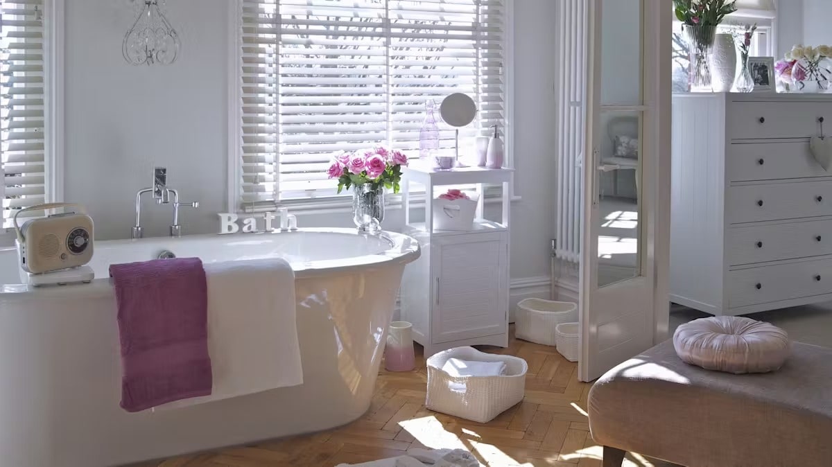 Przytulna łazienka utrzymana w jasnej kolorystyce z różowymi dodatkami.