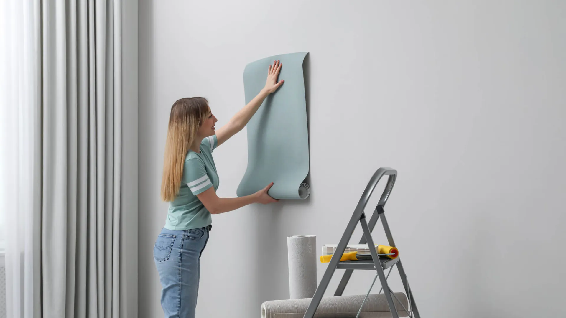 Kobieta przykłada tapetę do ściany