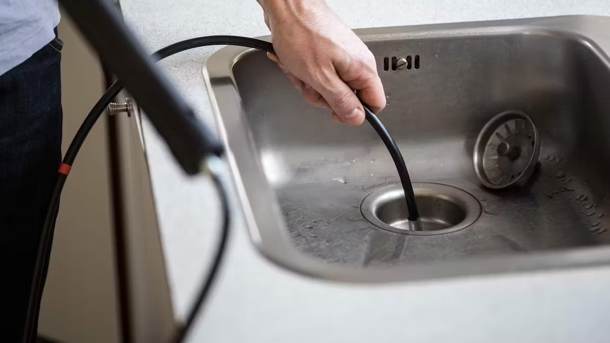 Udrażnianie zatkanego zlewu za pomocą spirali kanalizacyjnej.