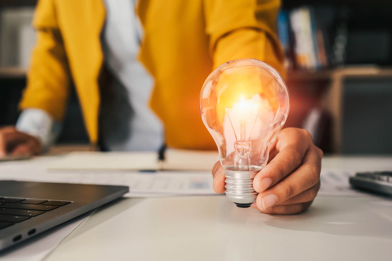 Doradca pokazuje żarówkę energooszczędną, która pozwoli zaoszczędzić na rachunkach za energię.