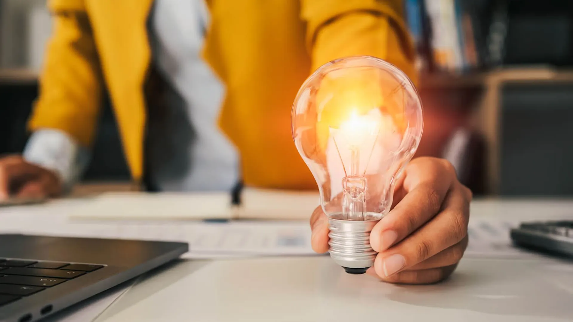Doradca pokazuje żarówkę energooszczędną, która pozwoli zaoszczędzić na rachunkach za energię.