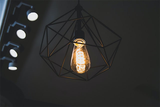Nowoczesna lampa z drucianym, czarnym abażurem. Wewnątrz dekoracyjna żarówka LED z widoczną spiralą.