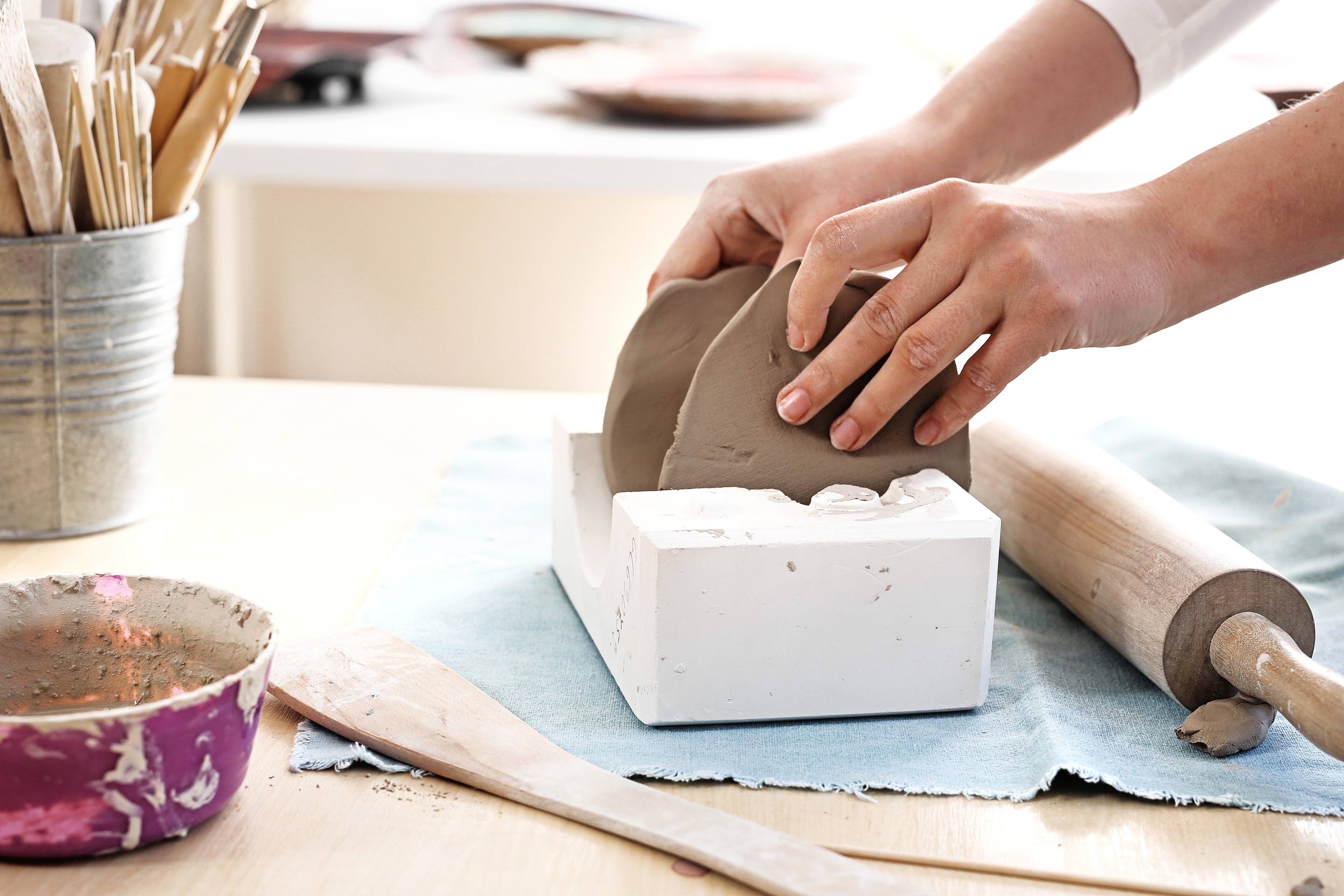 Kobieta wykonuje samodzielnie kubek na dzień taty z gliny ceramicznej.