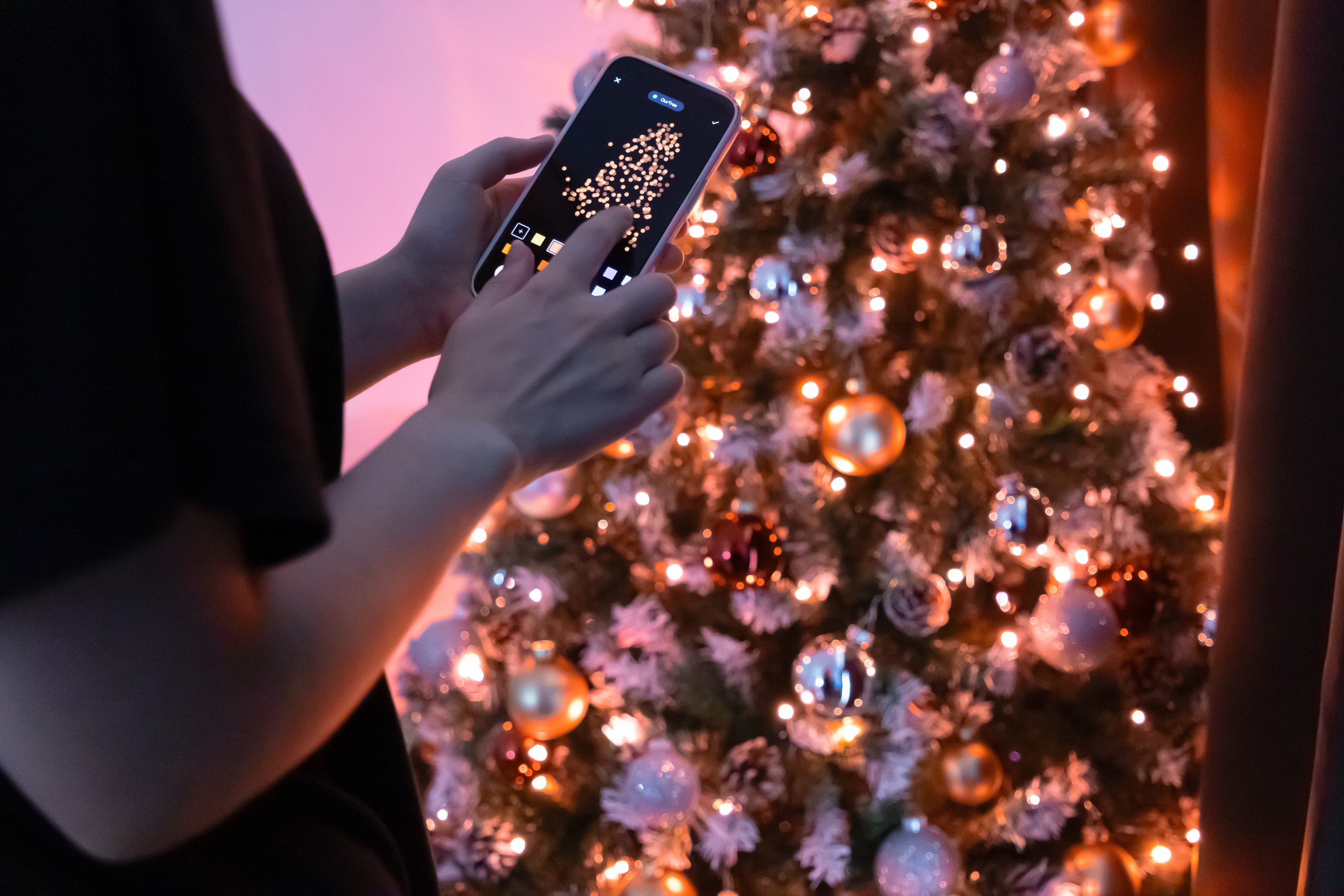 Mężczyzna zmienia oświetlenie choinki za pomocą aplikacji w telefonie