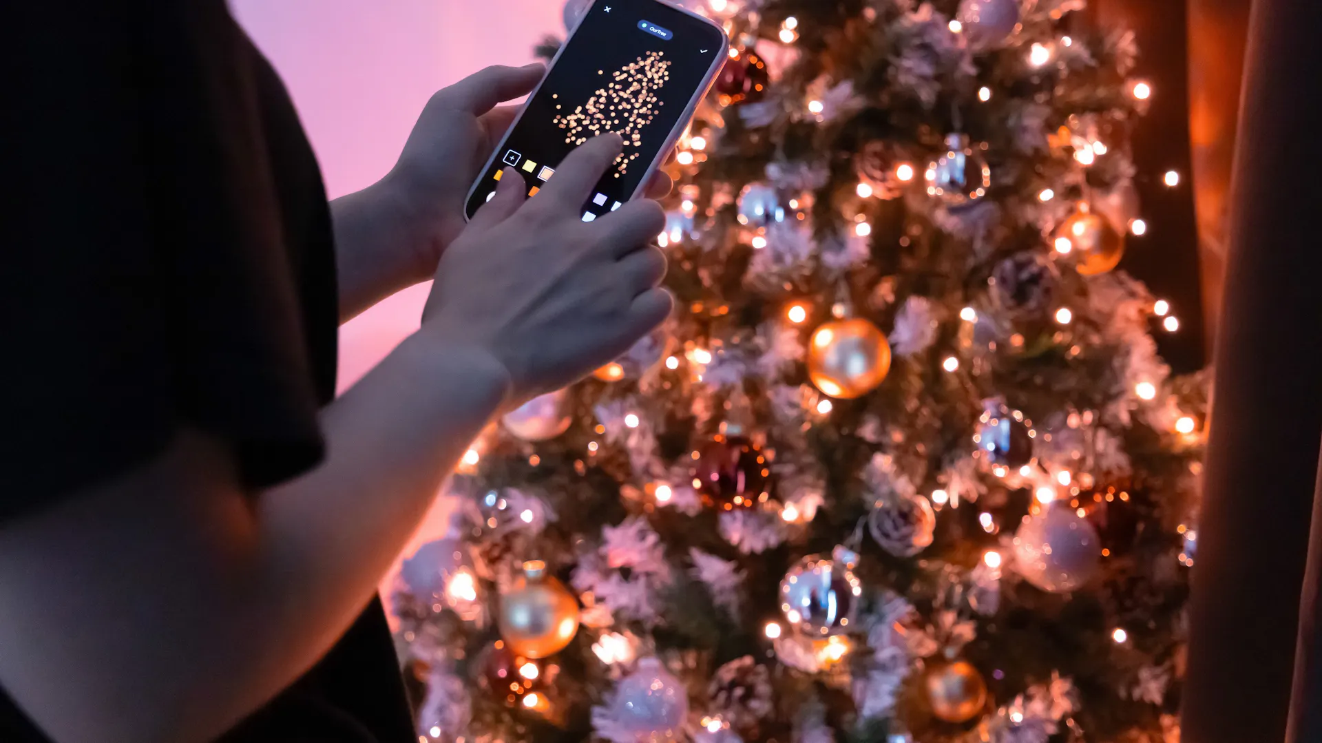 Mężczyzna zmienia oświetlenie choinki za pomocą aplikacji w telefonie