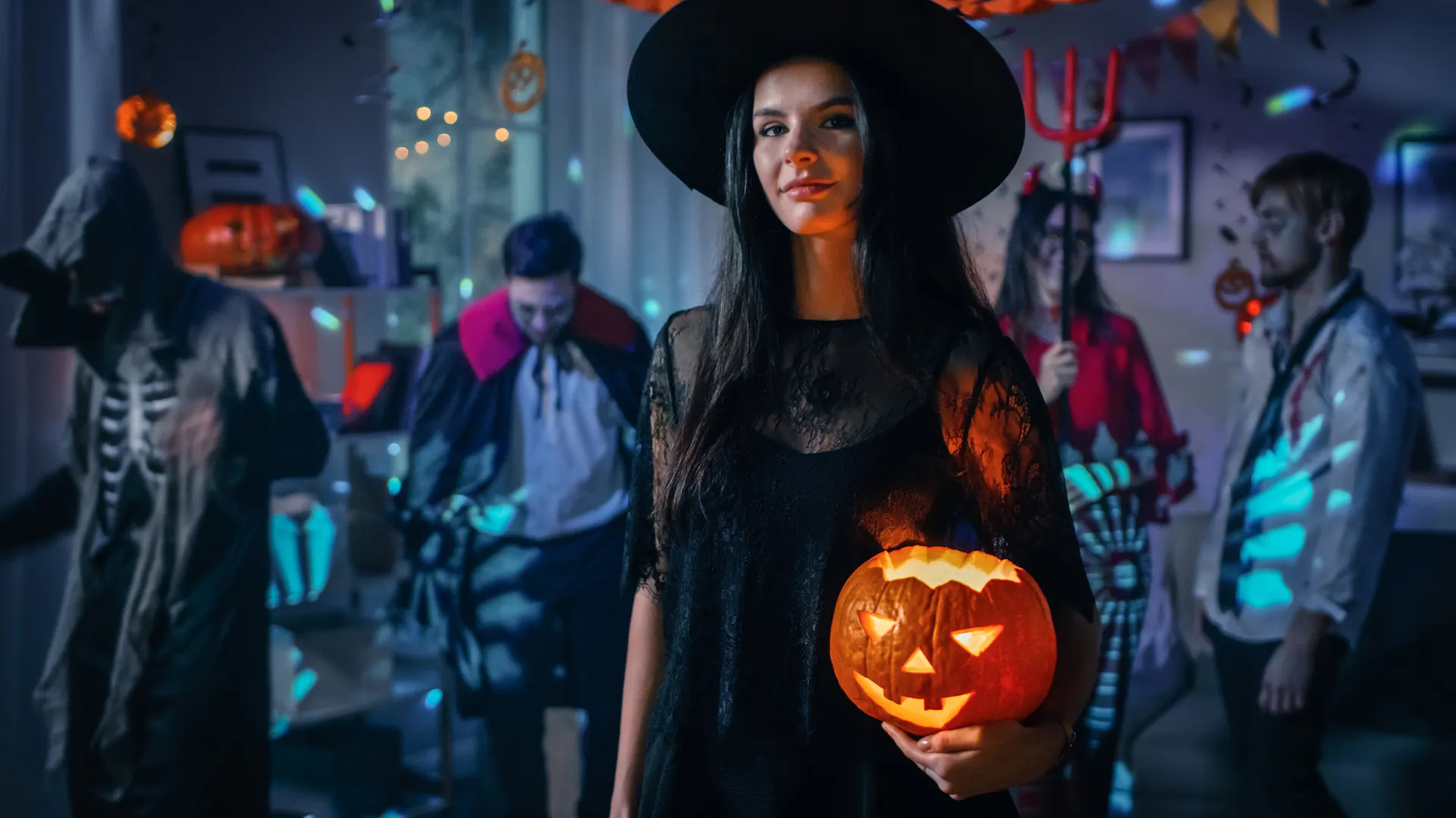 Młodzi ludzie bawią się na prywatce Halloween w przebraniach, wśród ozdób