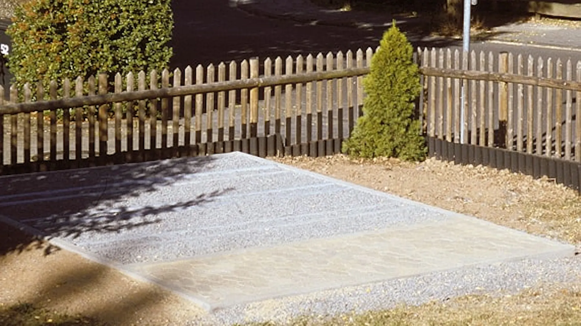 Fundament ciągły z kostki brukowej, obrzeży i kamienia. W tle drewniany płot.