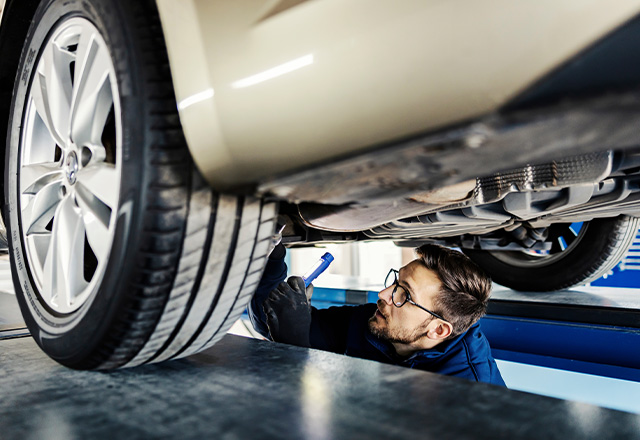 Mężczyzna naprawia auto w kanale samochodowym