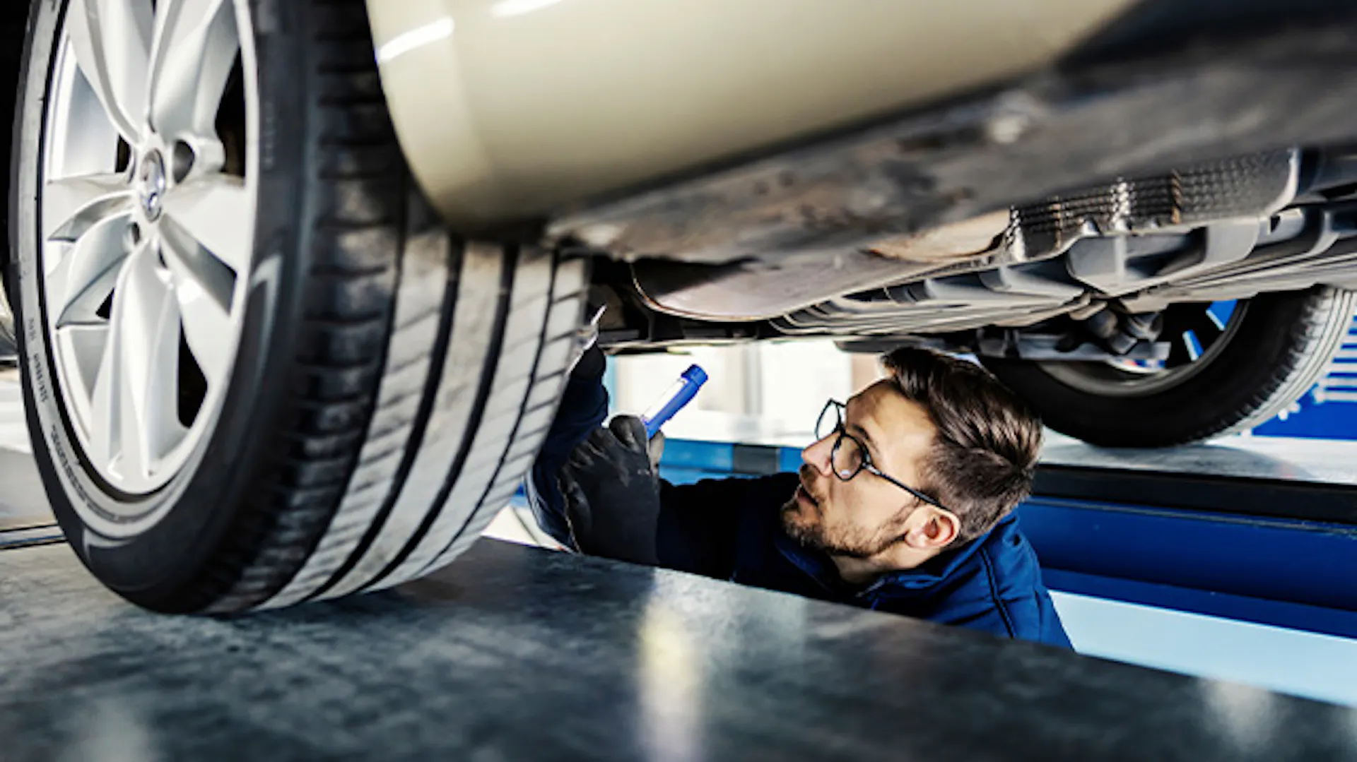 Mężczyzna naprawia auto w kanale samochodowym