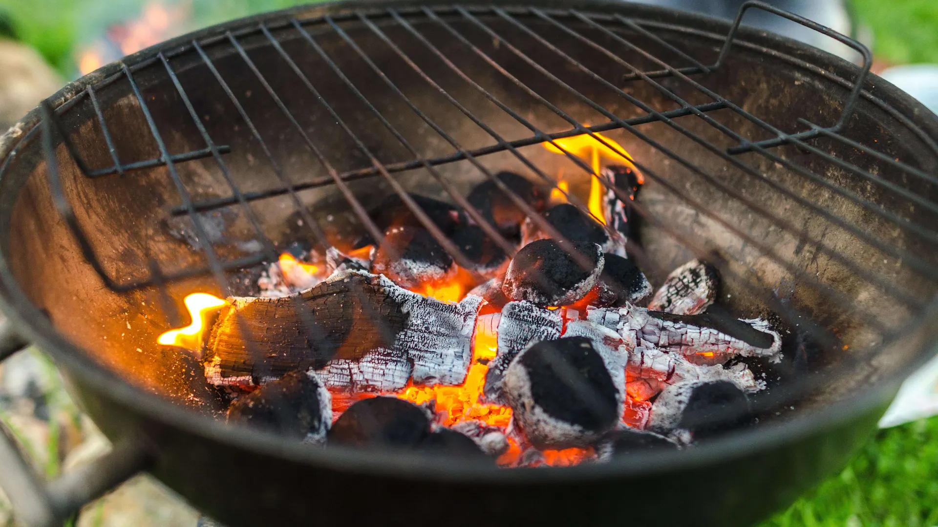 Okrągły grill węglowy. Wewnątrz rozżarzone węgle.