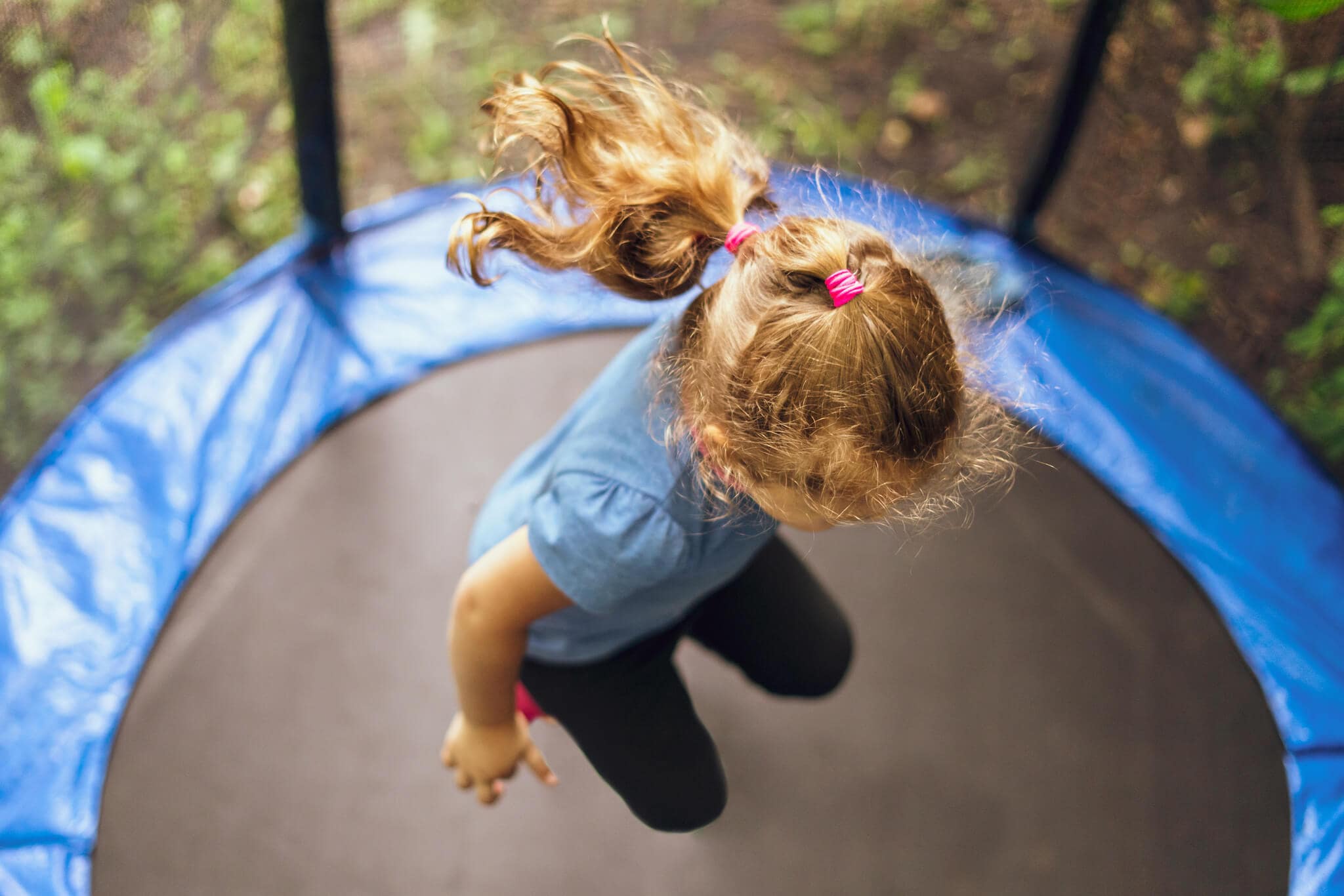 Dziewczynka skacze na niedrogiej trampolinie ogrodowej