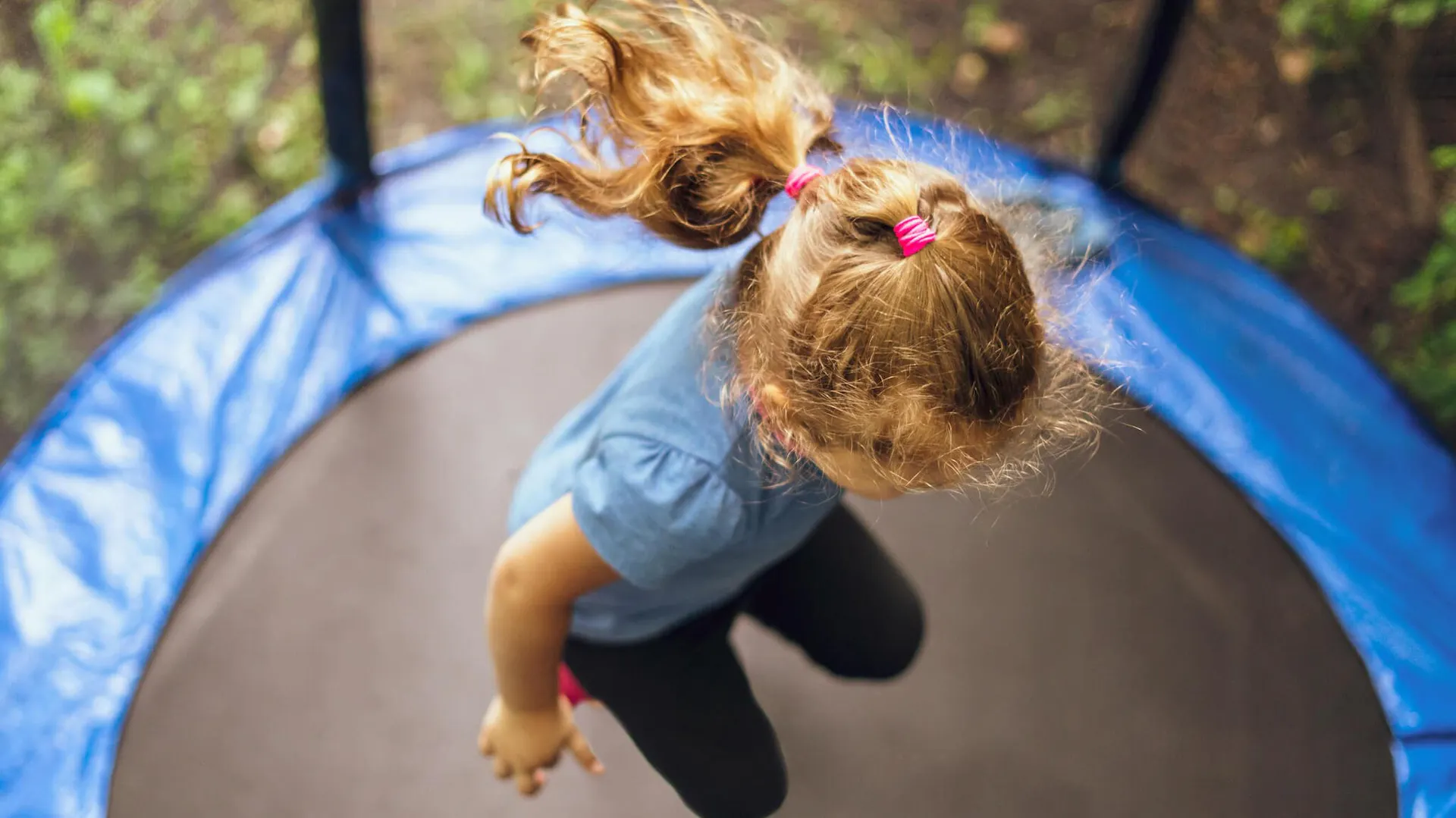 Dziewczynka skacze na niedrogiej trampolinie ogrodowej