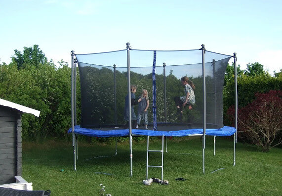 Dzieci bawią się na dużej, bezpiecznej trampolinie ogrodowej