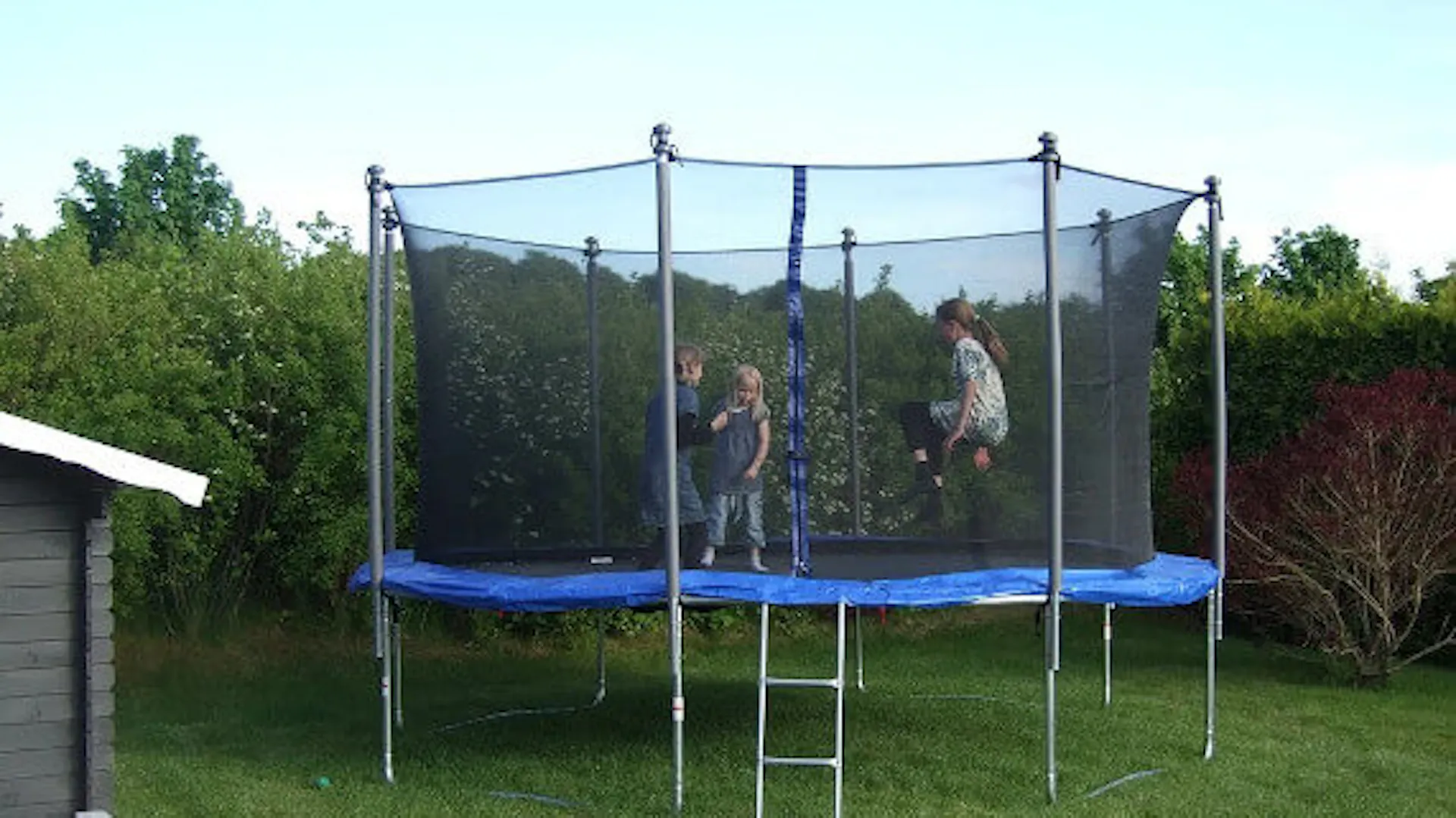 Dzieci bawią się na dużej, bezpiecznej trampolinie ogrodowej