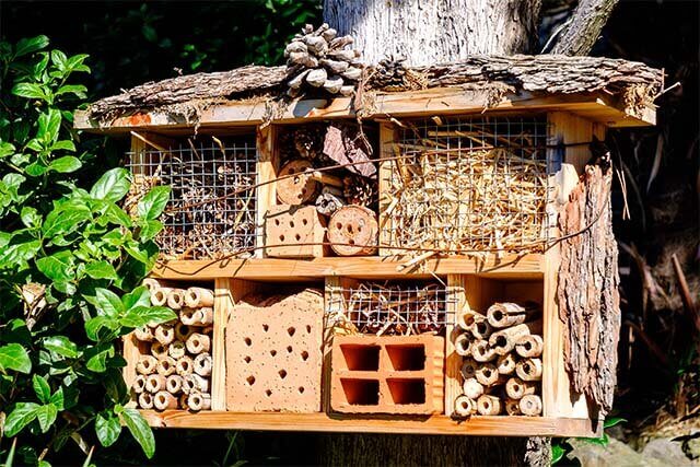 Duży domek dla owadów z 7 przegrodami, obity z zewnątrz korą.
