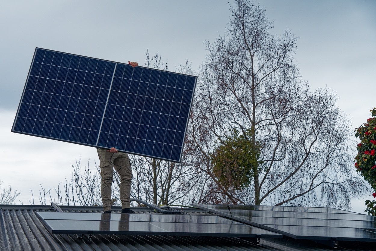 Mężczyzna montuje panele solarne na dachu skośnym