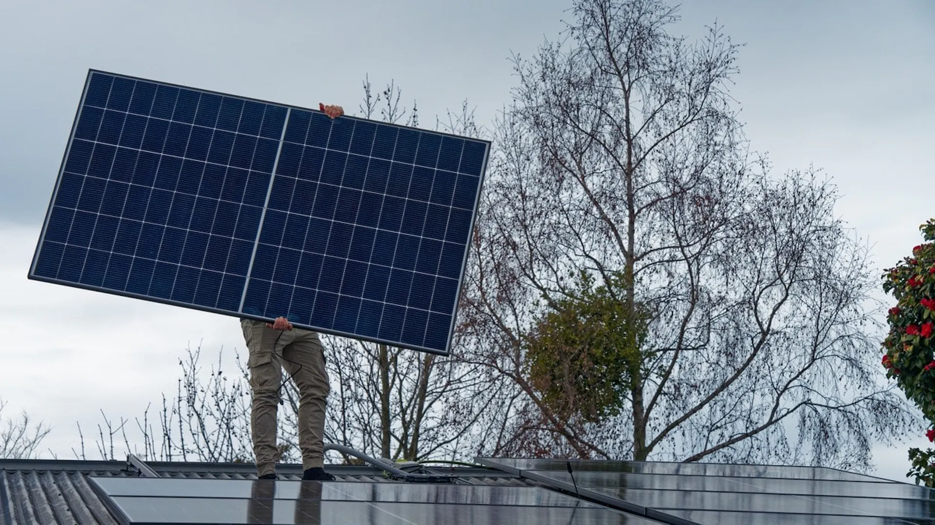 Mężczyzna montuje panele solarne na dachu skośnym