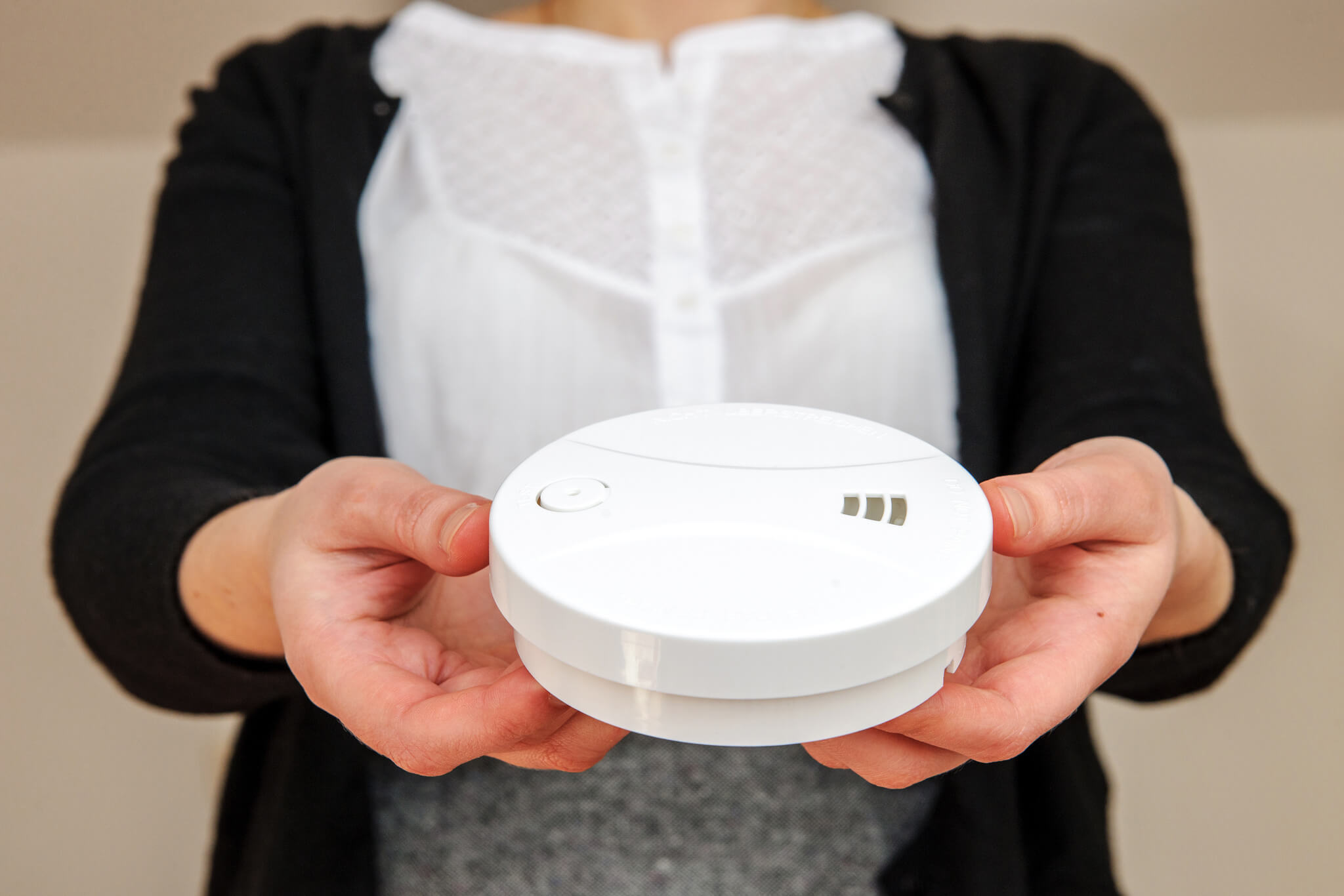 Kobieta w wyciągniętych przed siebie dłoniach trzyma czujnik czadu
