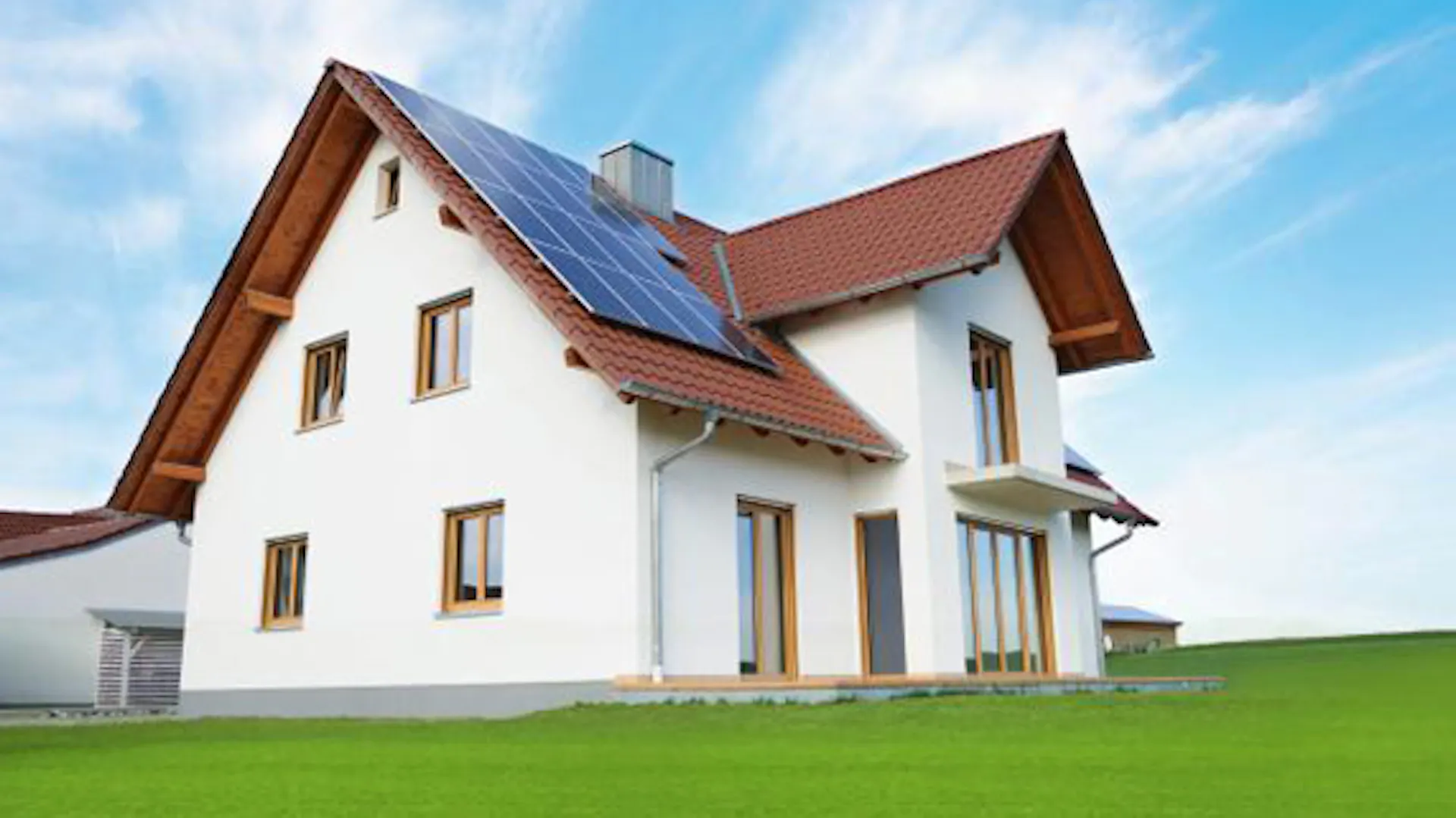 Dom jednorodzinny z instalacją solarną i zielonym trawnikiem.