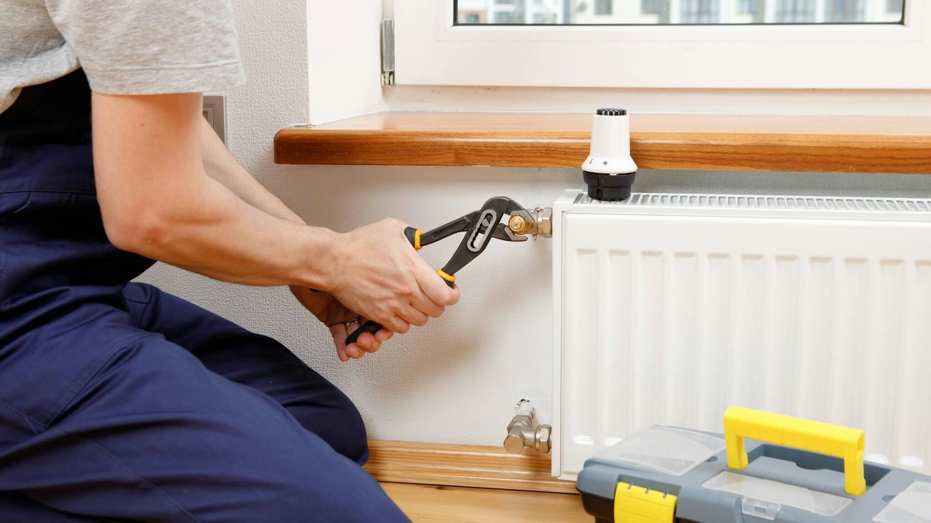 mężczyzna przykręcający grzejnik kluczem francuskim