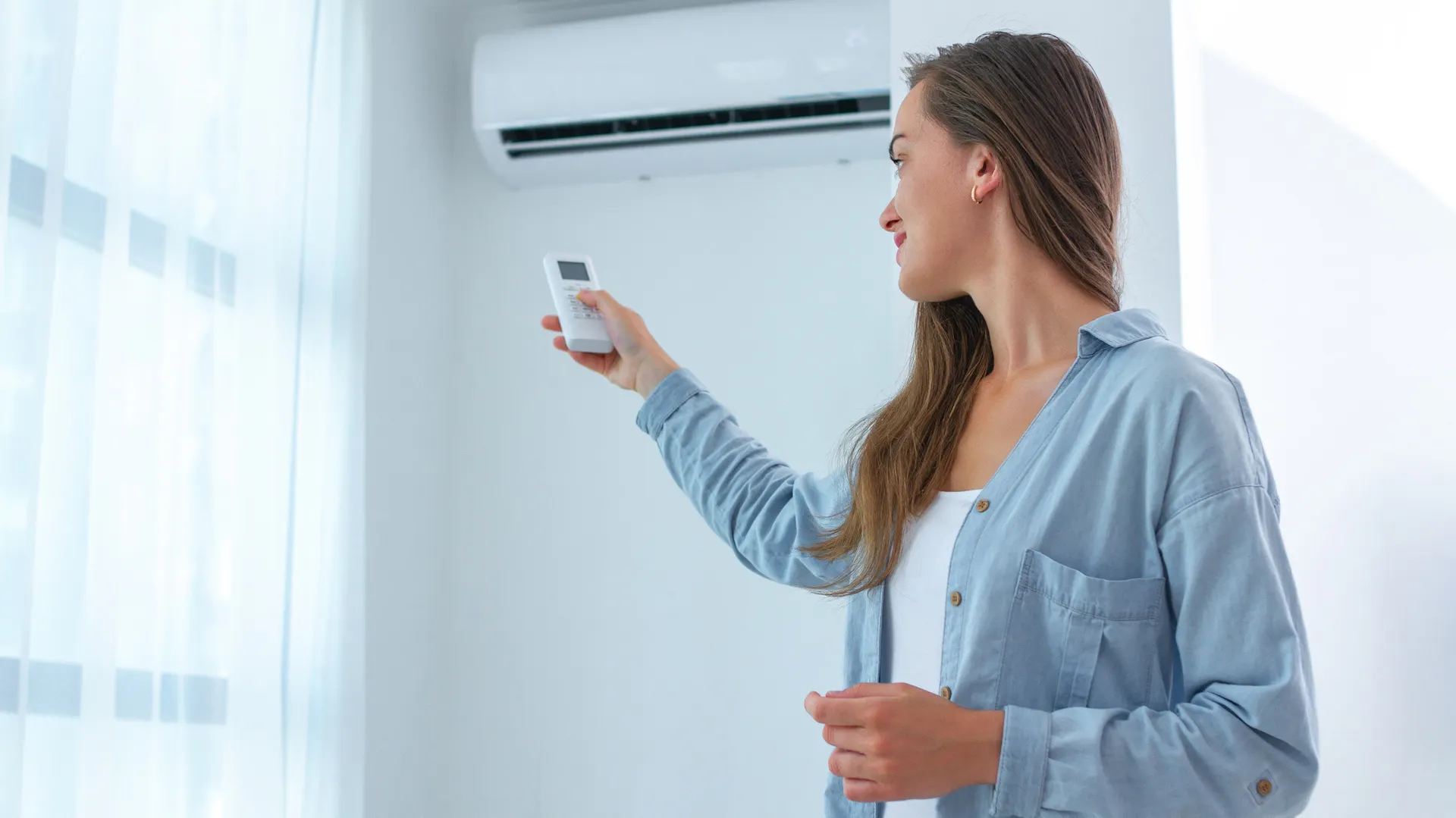 Kobieta reguluje klimatyzację w domu za pomocą pilota