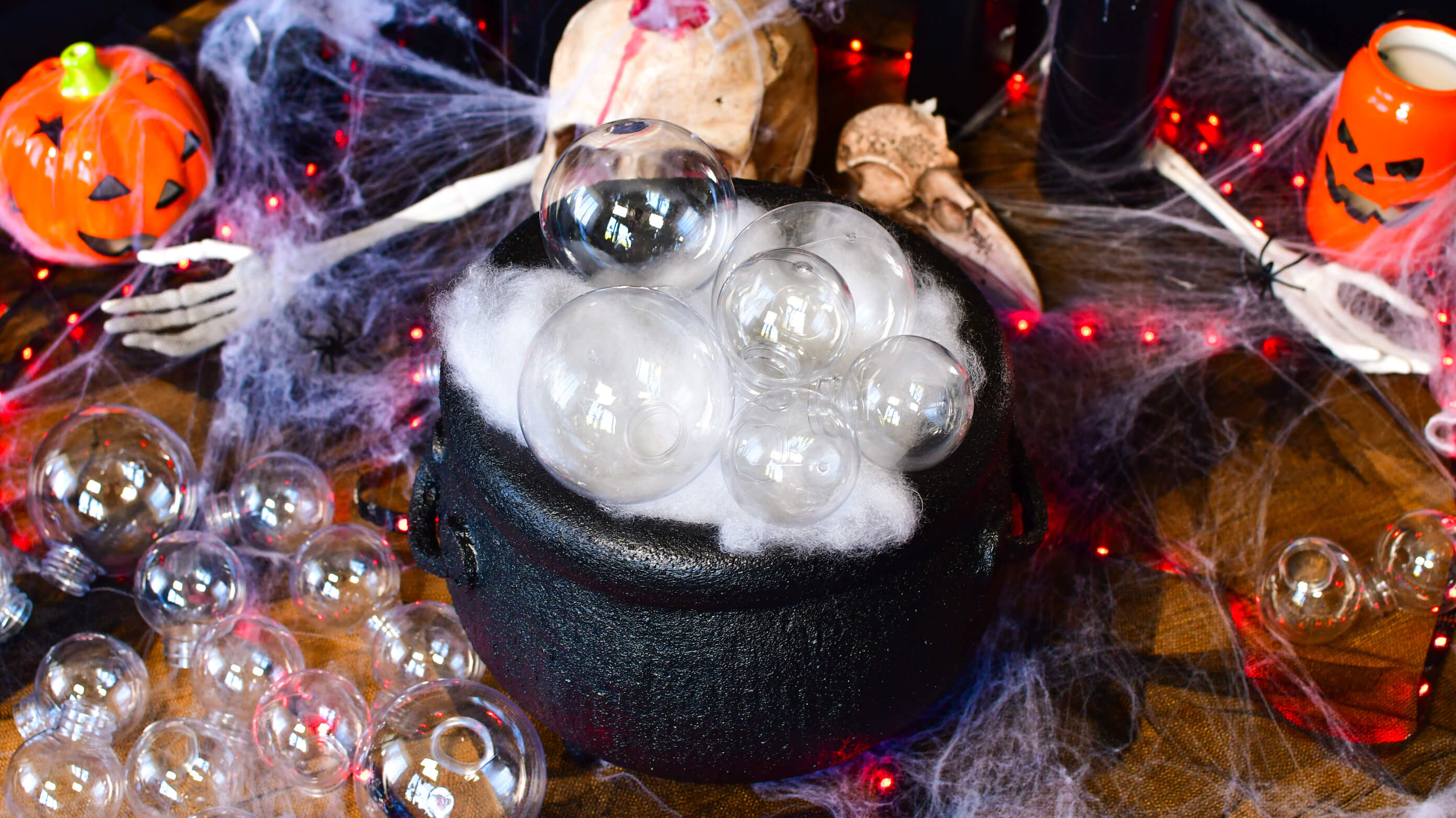 Układanie przezroczystych baniek na wacie w czasie tworzenia dekoracji na Halloween - kociołek czarownicy