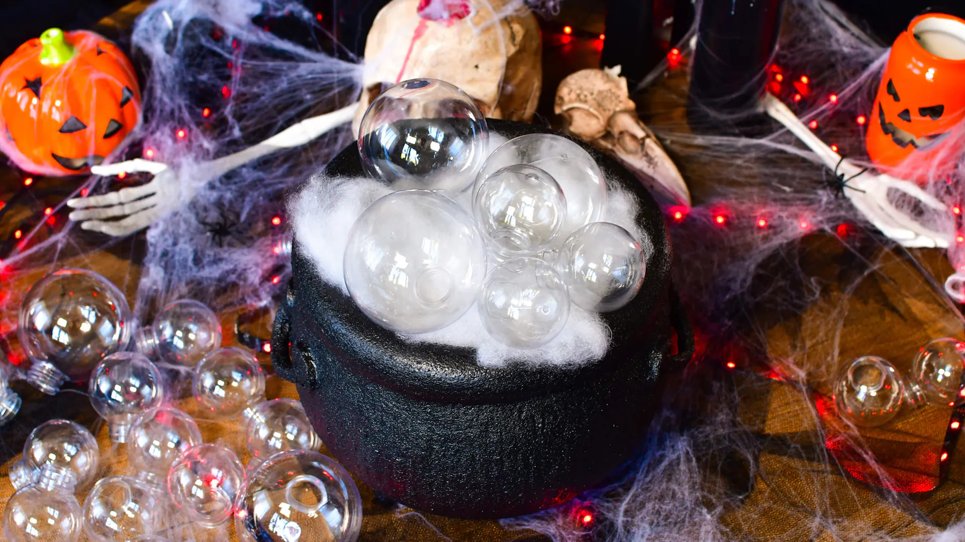 Układanie przezroczystych baniek na wacie w czasie tworzenia dekoracji na Halloween - kociołek czarownicy