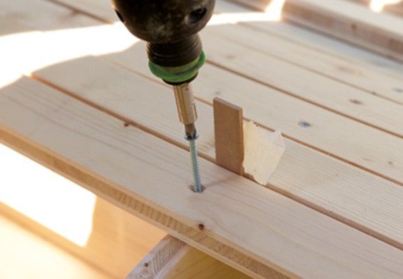 Krok 2 instrukcji DIY polega na przykręceniu listewek do stelaża huśtawki ogrodowej.