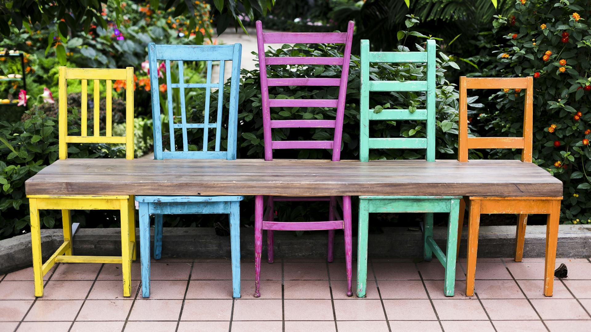 Buntgestrichene Stühle mit einer durchgehenden Sitzfläche zur Sitzbank gestaltet